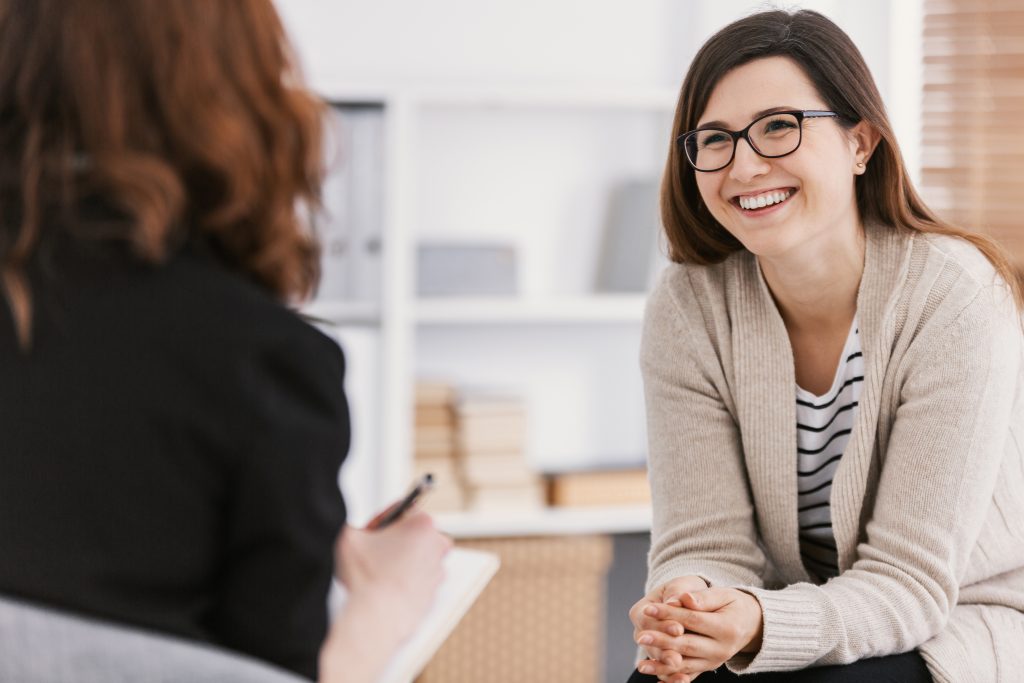 Happy woman during successful psychotherapy with counselor at clinic