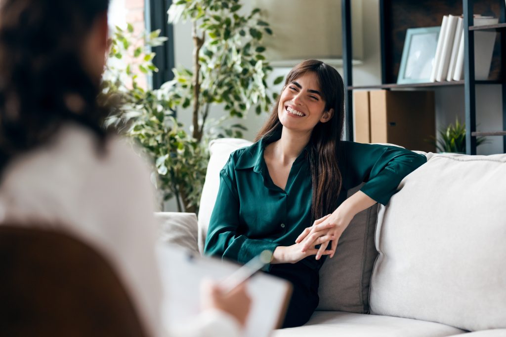 Shot of beautiful woman having therapy while the psychologist takes notes, sitting on the couch in the psychology office